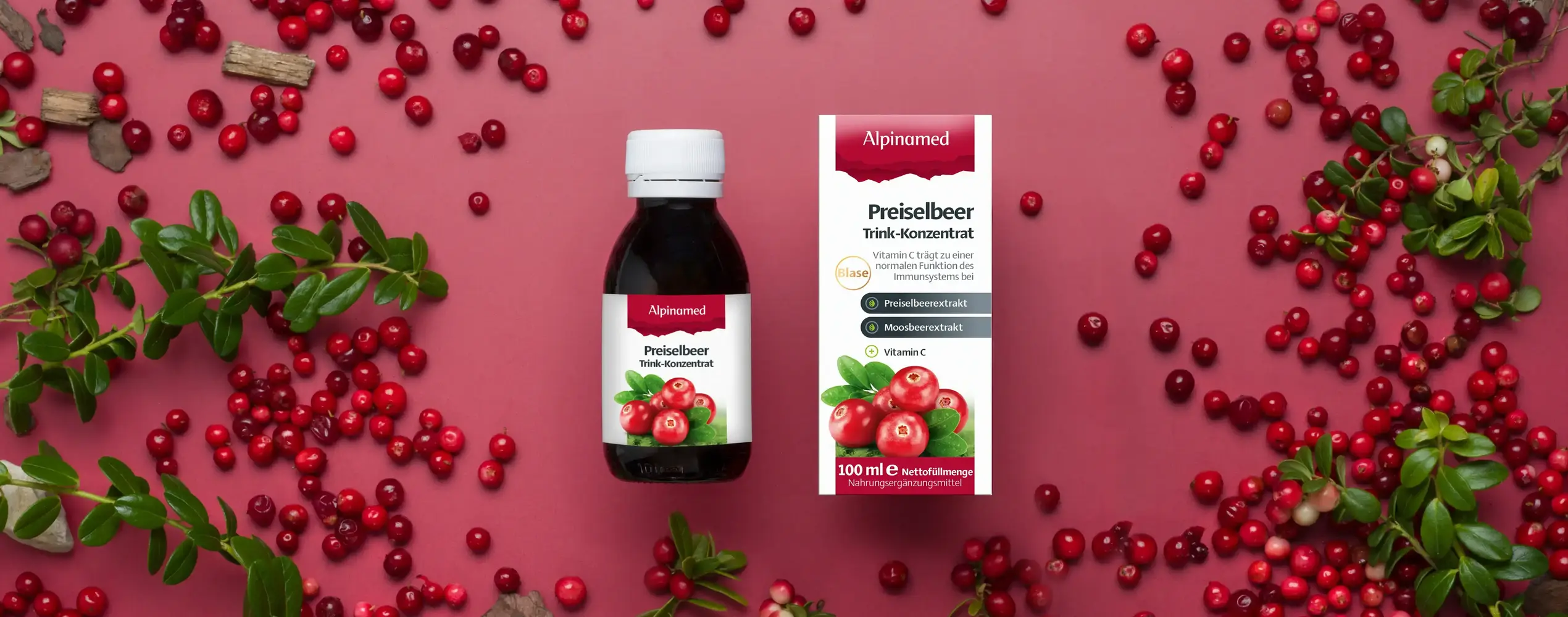 Alpinamed Preiselbeer Trinkkonzentrat liegend mit Preiselbeeren daneben